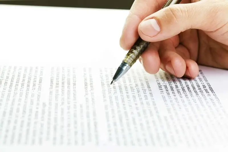 Bolígrafo en mano revisando textos y aplicando correcciones sobre la hoja escrita